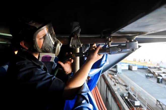 A sailor removes deteriorated paint and rust with a disc sander on a weather deck aboard the aircraft carrier USS Ronald Reagan on Sept. 6, 2012. U.S. Navy Photo