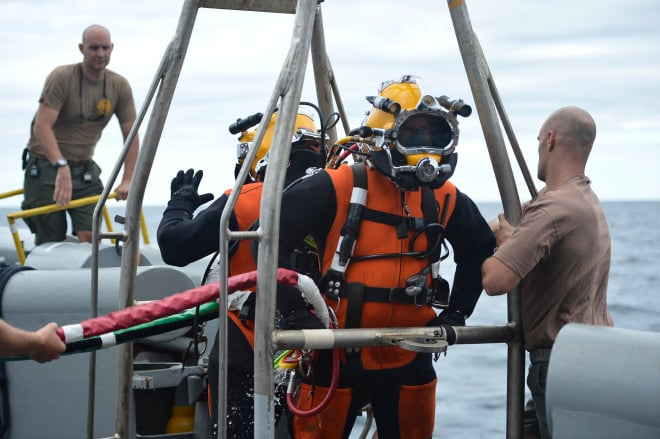 Divers, assigned to Mobile Diving Salvage Unit 2, Company 2-4, wait on the diving stage to be lowered into the water during air surface supplied diving operations off the coast of Virginia on Aug. 16, 2013. US Navy Photo