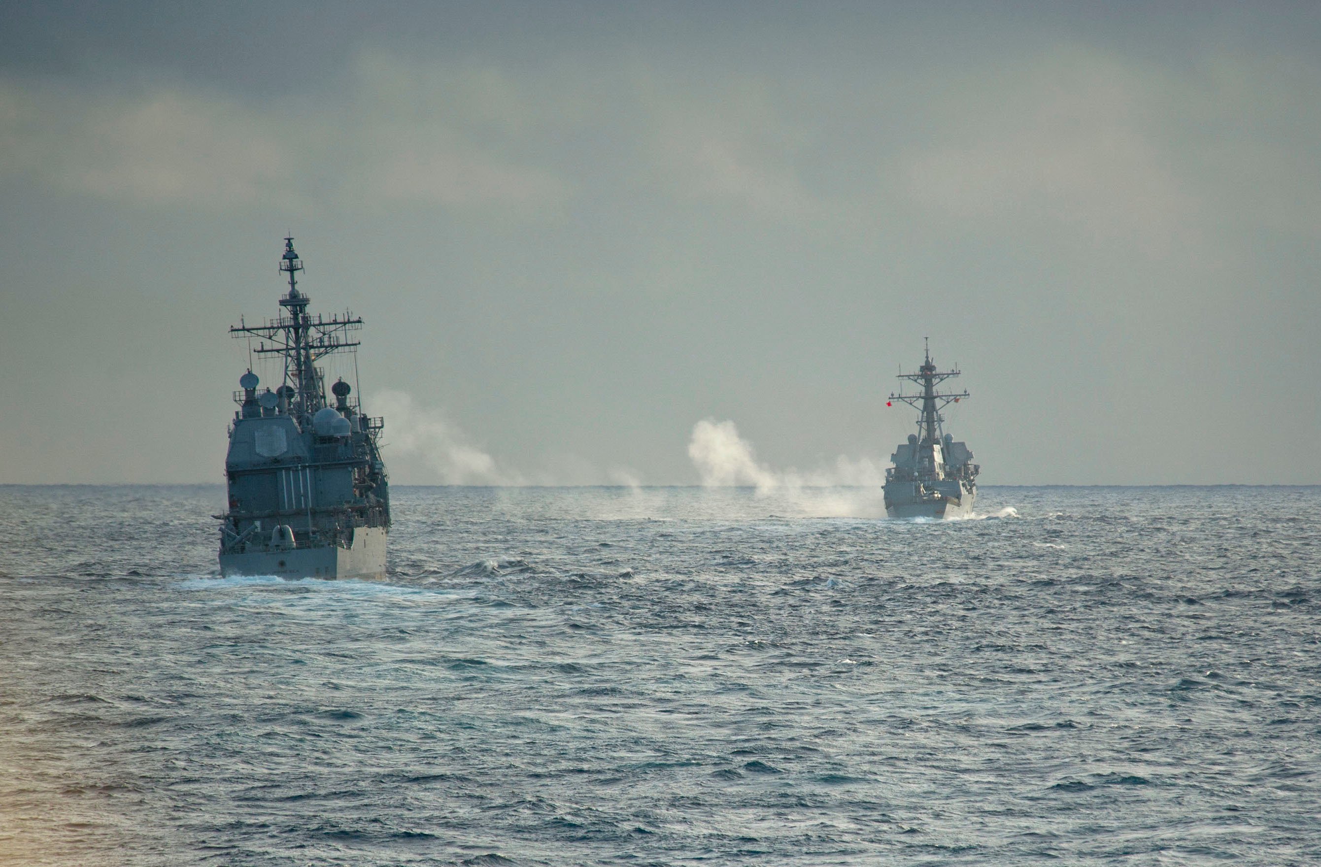 USS Philippine Sea (CG-58), right, fires a 5-inch gun during a live fire exercise with the guided-missile destroyers USS Truxton (DDG-103) on Feb. 20, 2014. US Navy Photo