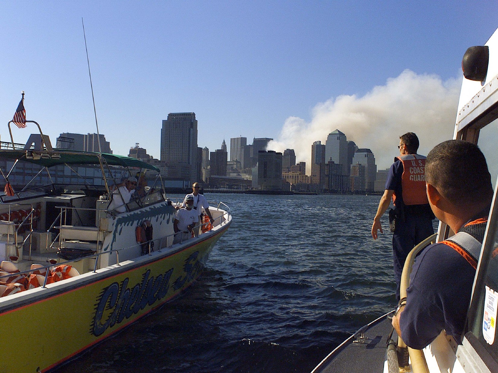 A Coast Guard boarding team aboard a 41-footer looks over a privately owned vessel in New York Harbor as the World Trade Center site burns in the background. US Coast Guard Photo