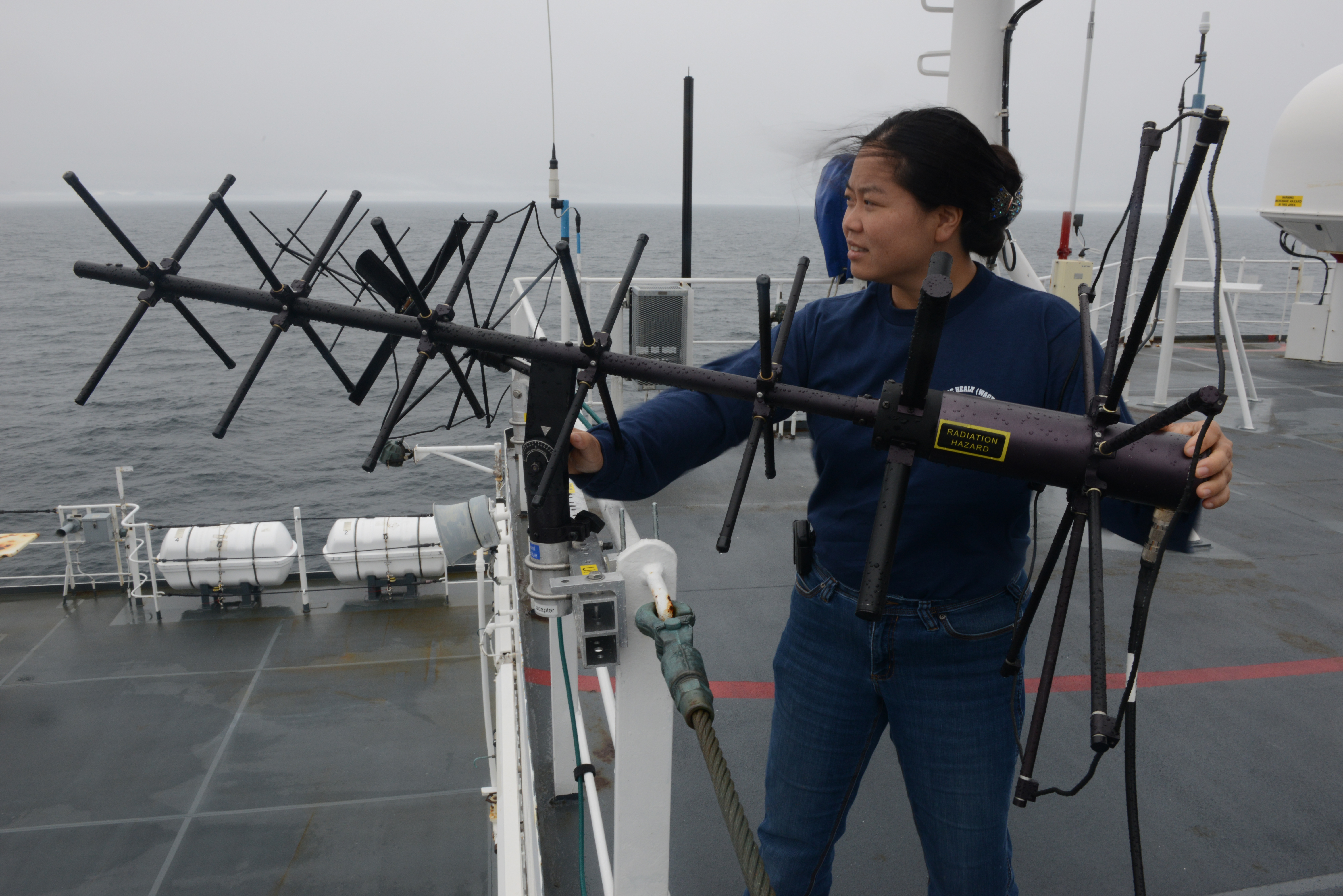 Amy Sun, an advanced program lead for Lockheed-Martin, adjusts a UHF antenna aboard USCGC Healy (WAGB-20) while underway near Alaska on Aug. 10, 2014.