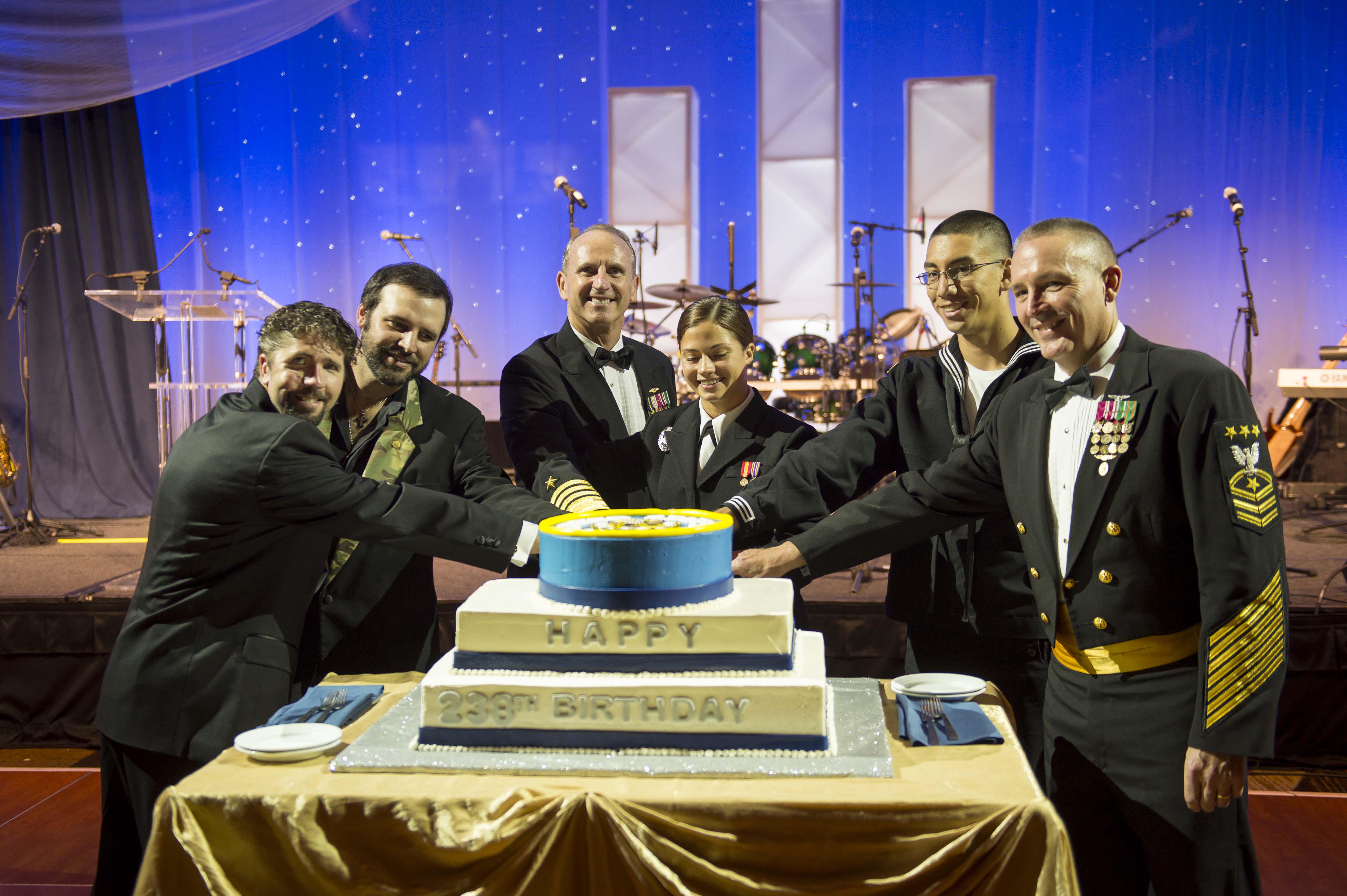 Navy SEAL Lt. Jason Redman, country music singer Mark Wills, Chief of Naval Operations (CNO) Adm. Jonathan Greenert, the two youngest Sailors in attendance and Master Chief Petty Officer of the Navy Mike Stevens cut a birthday cake together at the U.S. Navy Birthday Ball in Washington, DC in 2013. US Navy Photo