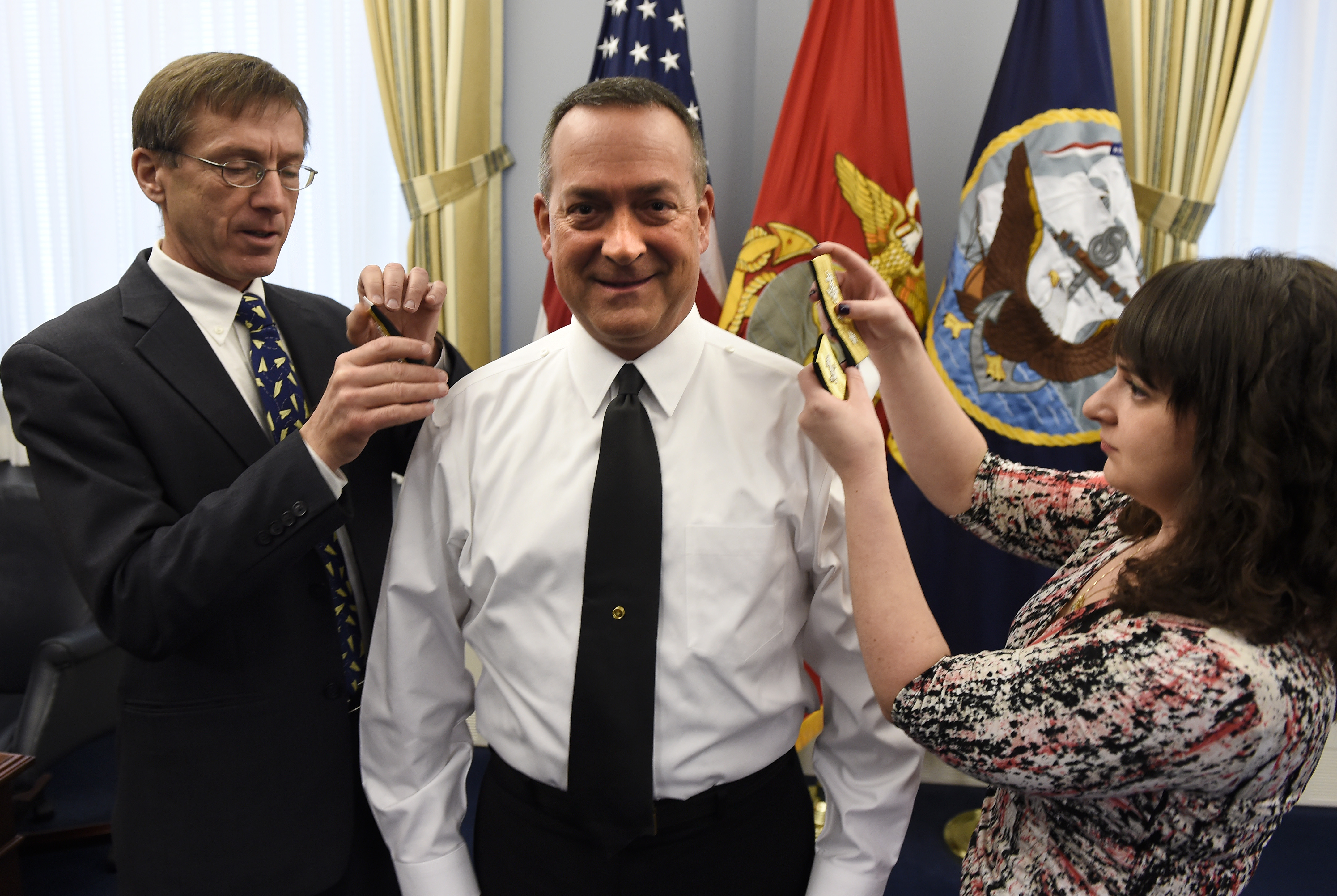 Sean J. Stackley, assistant secretary of the Navy for research development and acquisition, joins Rear Adm. Mathias Winter's daughter as they replace his one-star shoulder boards with two-star shoulder boards. US Navy Photo