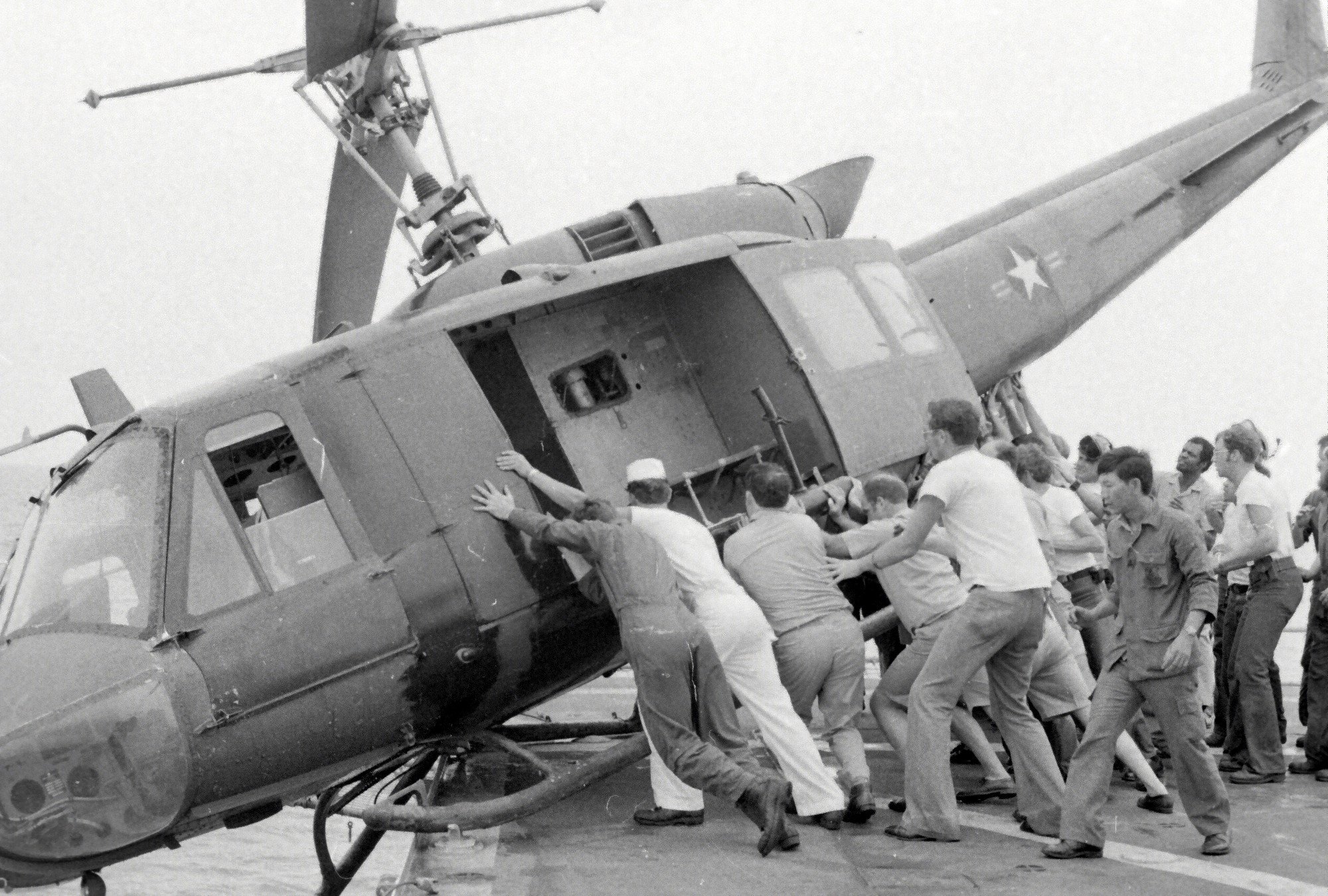Personnel pus a UH-1 Iroquois off the deck of USS Kirk at the close of the Vietnam War. 