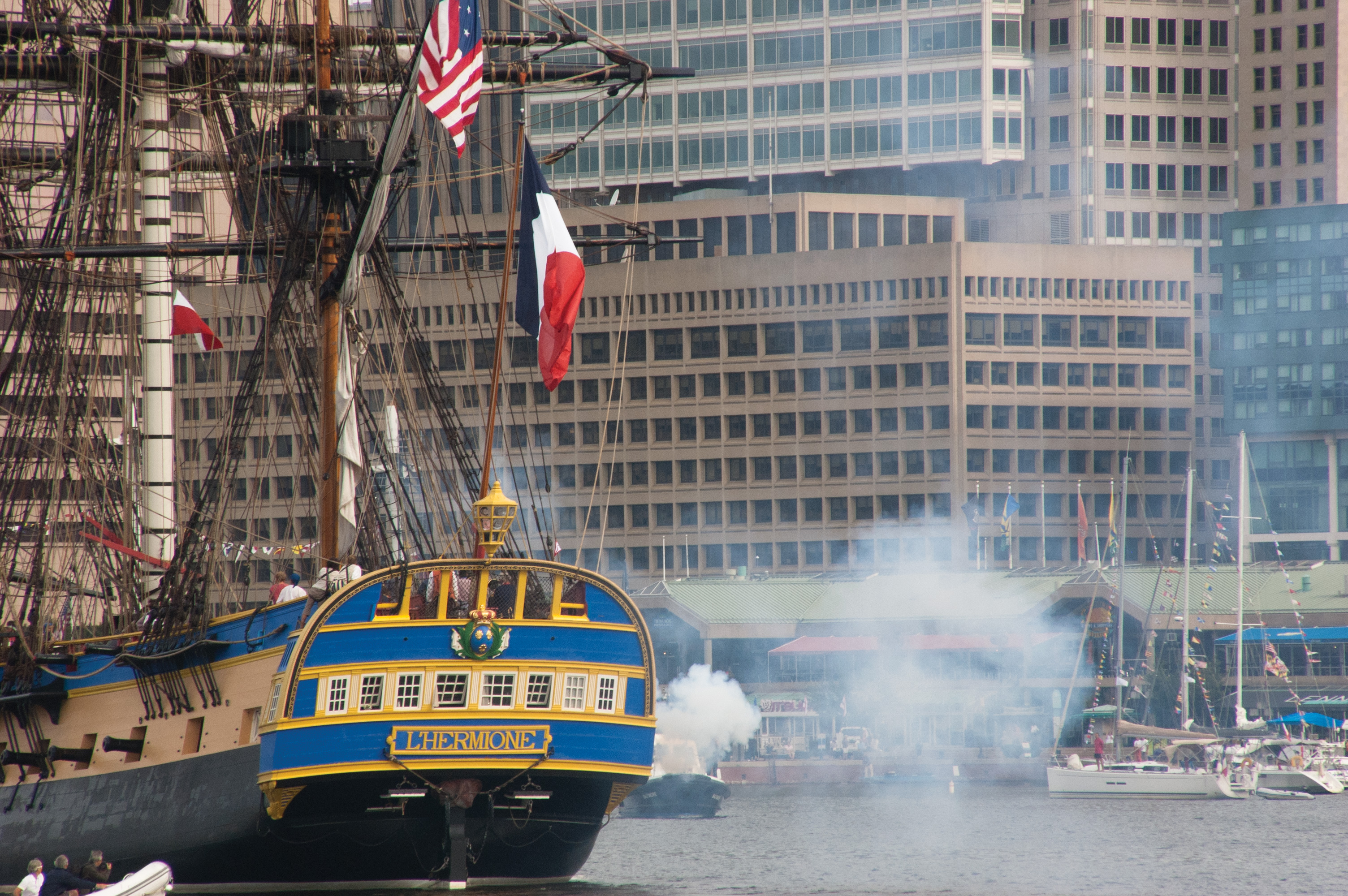 The replica Hermione fires a series of blank rounds to greet the city of Baltimore. USNI News photo.