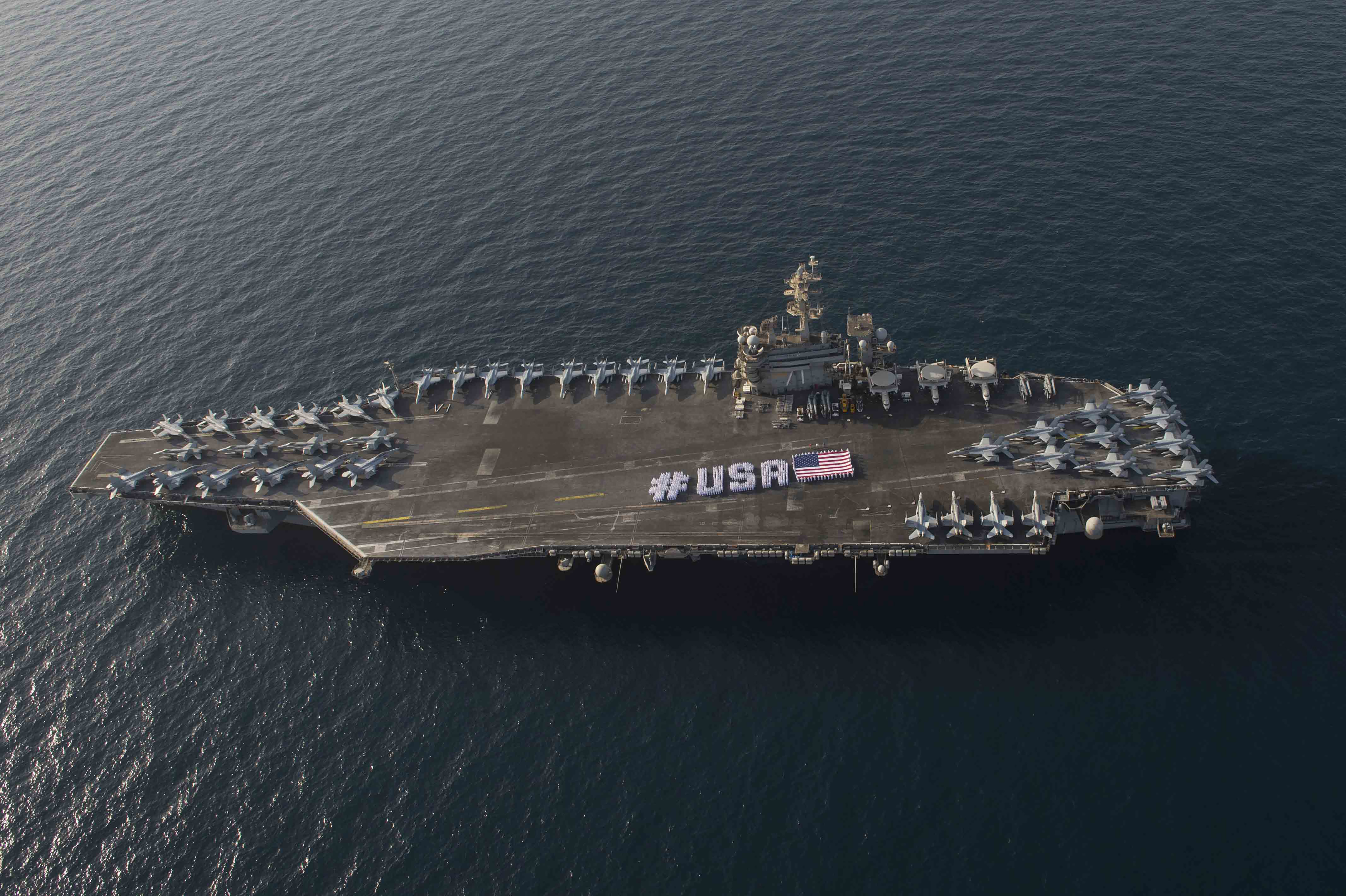 Sailors spell out #USA with the American flag on the flight deck of the aircraft carrier USS Theodore Roosevelt in honor of the nation's upcoming Independence Day weekend on June 28, 2015. US Navy Photo