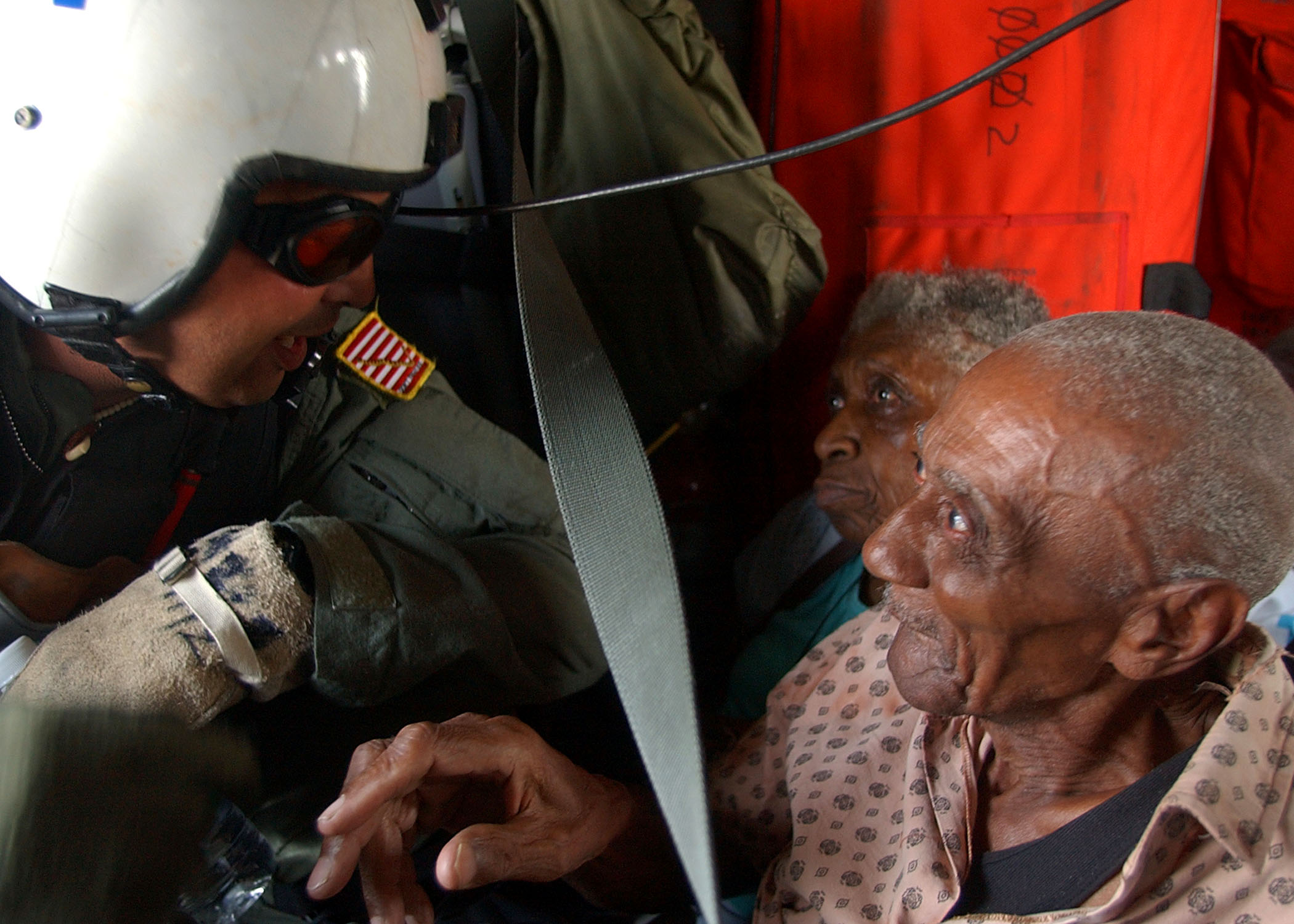 Navy Search and Rescue (SAR) Swimmer Aviation Warfare Systems Operator 1st Class Scott Chun calms victims of Hurricane Katrina after rescuing them from a rooftop in downtown New Orleans on Sept. 2, 2005. US Navy Photo