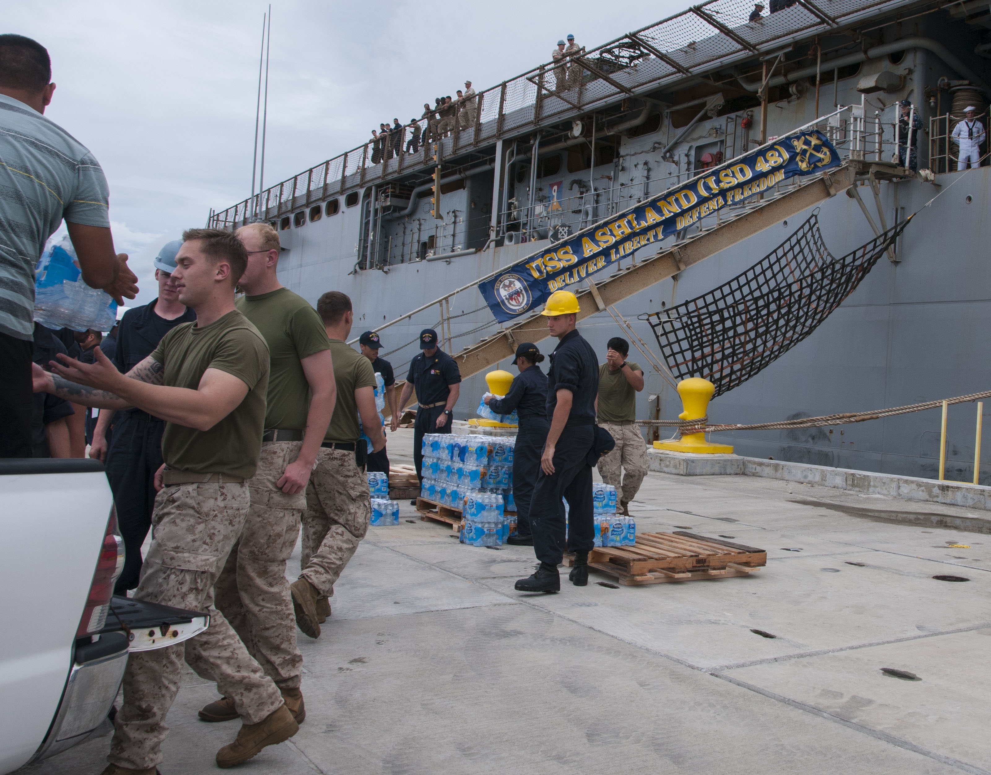 Sailors and Marines load cases of water onto the amphibious dock landing ship USS Ashland (LSD 48) in preparation for the ship getting underway to deploy to Saipan on Aug. 6, 2015. US Navy Photo
