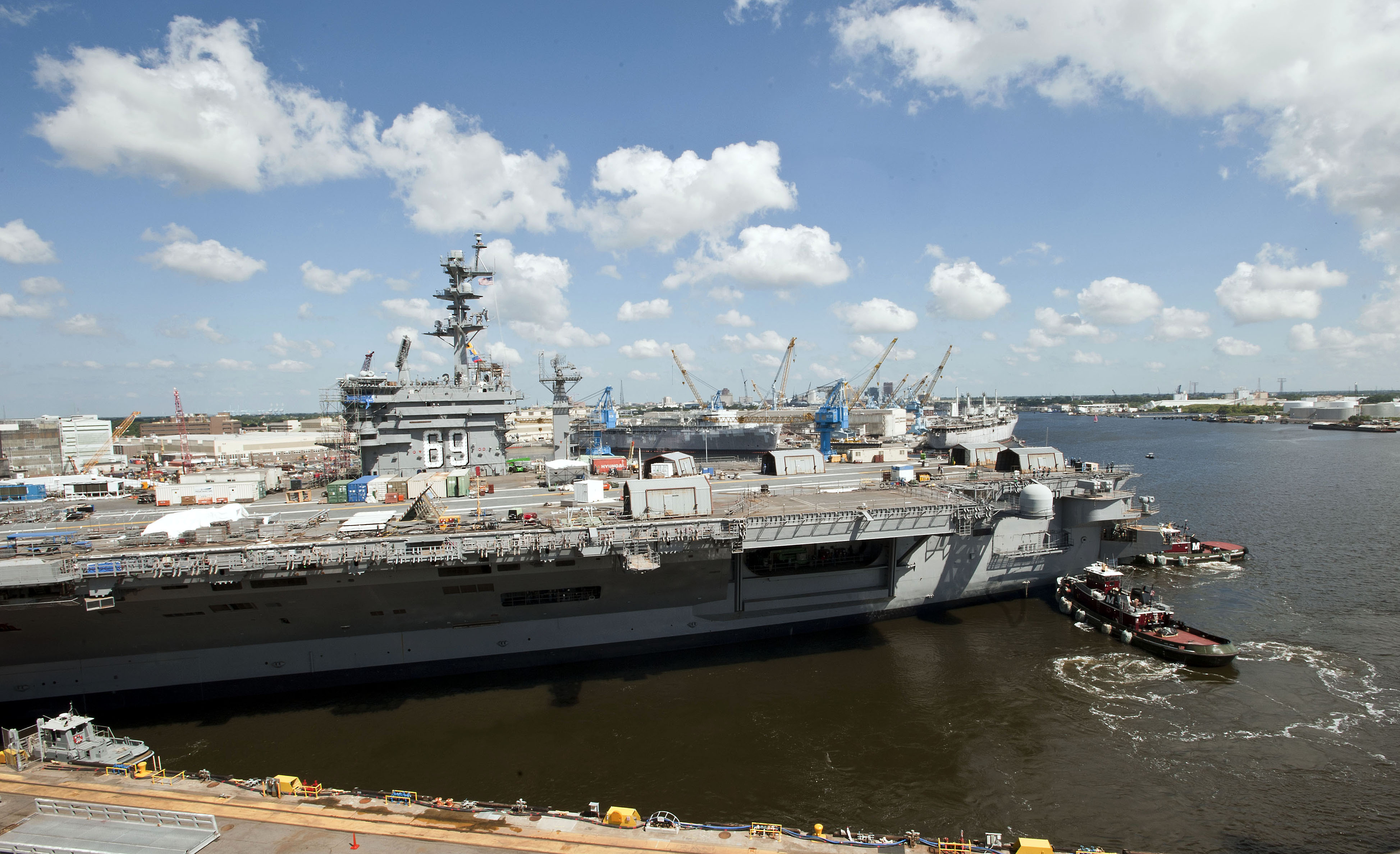 Tugboats guide the aircraft carrier USS Dwight D. Eisenhower (CVN 69) from her dry dock at Norfolk Naval Shipyard to a nearby pier following a scheduled dock flooding earlier in the morning of Aug. 26, 2014. US Navy photo.