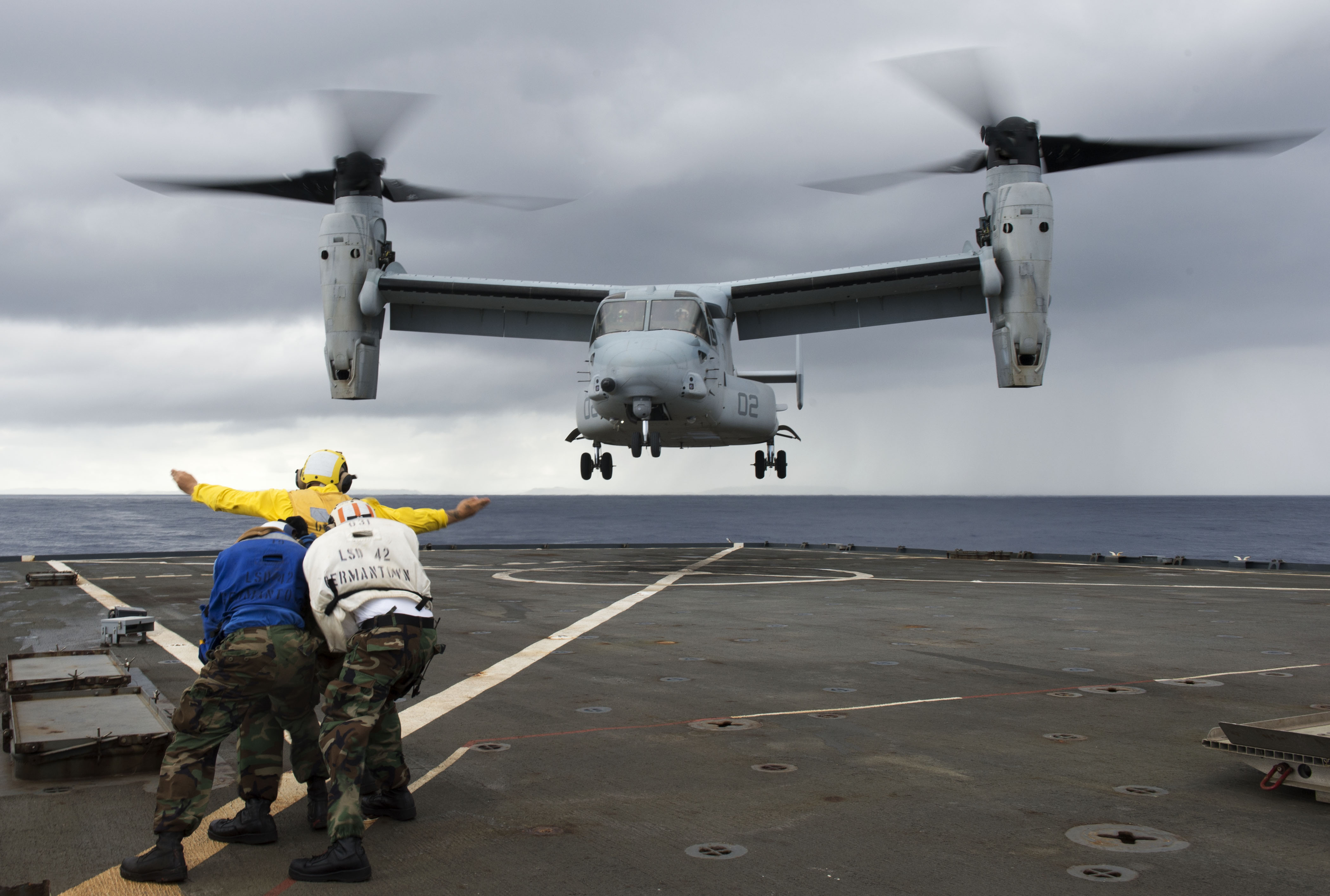 Sailors direct an MV-22 Osprey assigned to Marine Medium Tiltrotor Squadron (VMM) 265 as it lands on the flight deck of the amphibious dock landing ship USS Germantown (LSD 42) during exercise Blue Chromite off Okinawa in November 2014. US Navy photo.