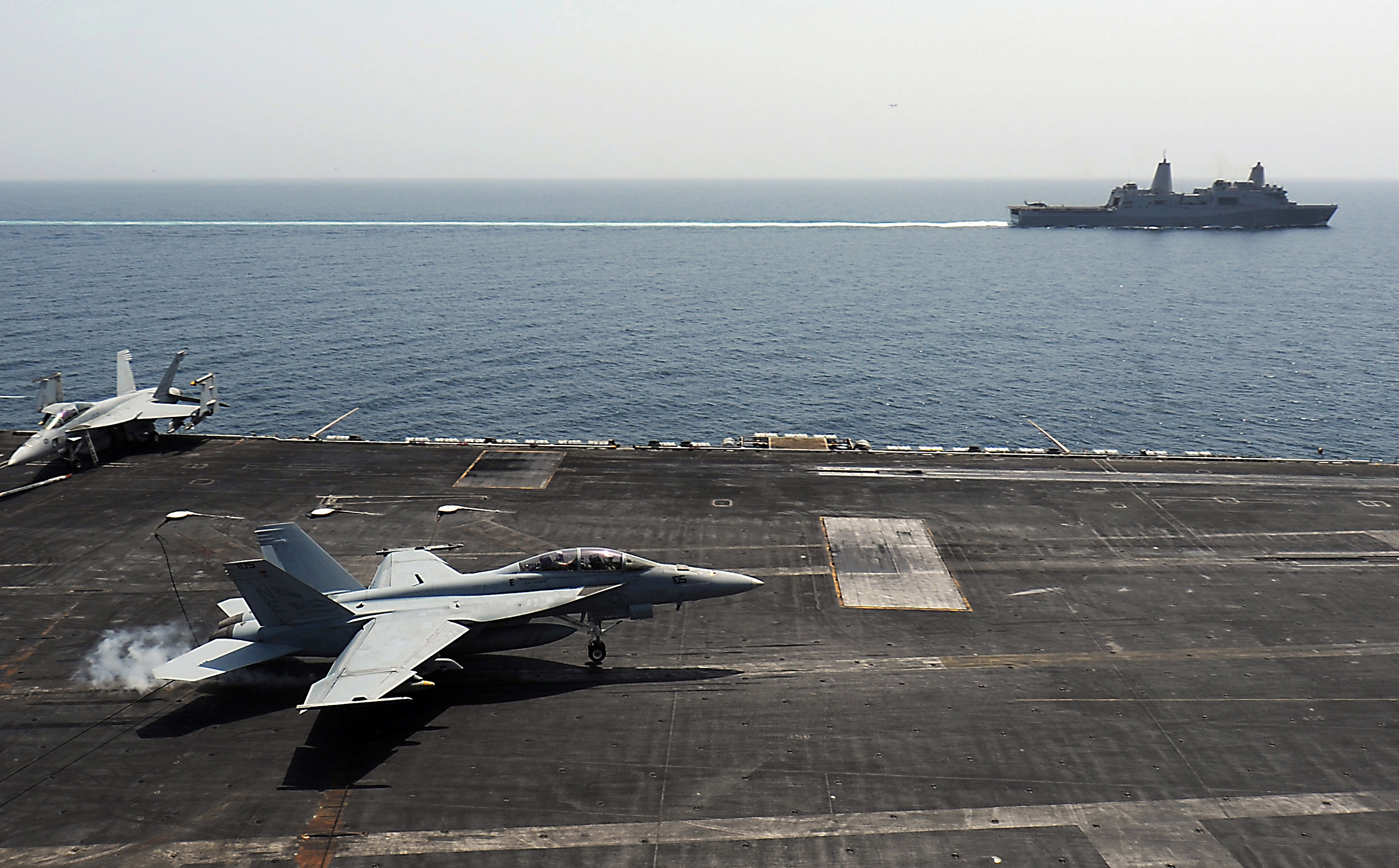 An F/A-18F Super Hornet assigned to the Bounty Hunters of Strike Fighter Squadron (VFA) 2 lands on the flight deck of the Nimitz-class aircraft carrier USS Abraham Lincoln (CVN 72) as the amphibious transport dock ship USS New Orleans (LPD 18) transits alongside in April 2012. US Navy photo.