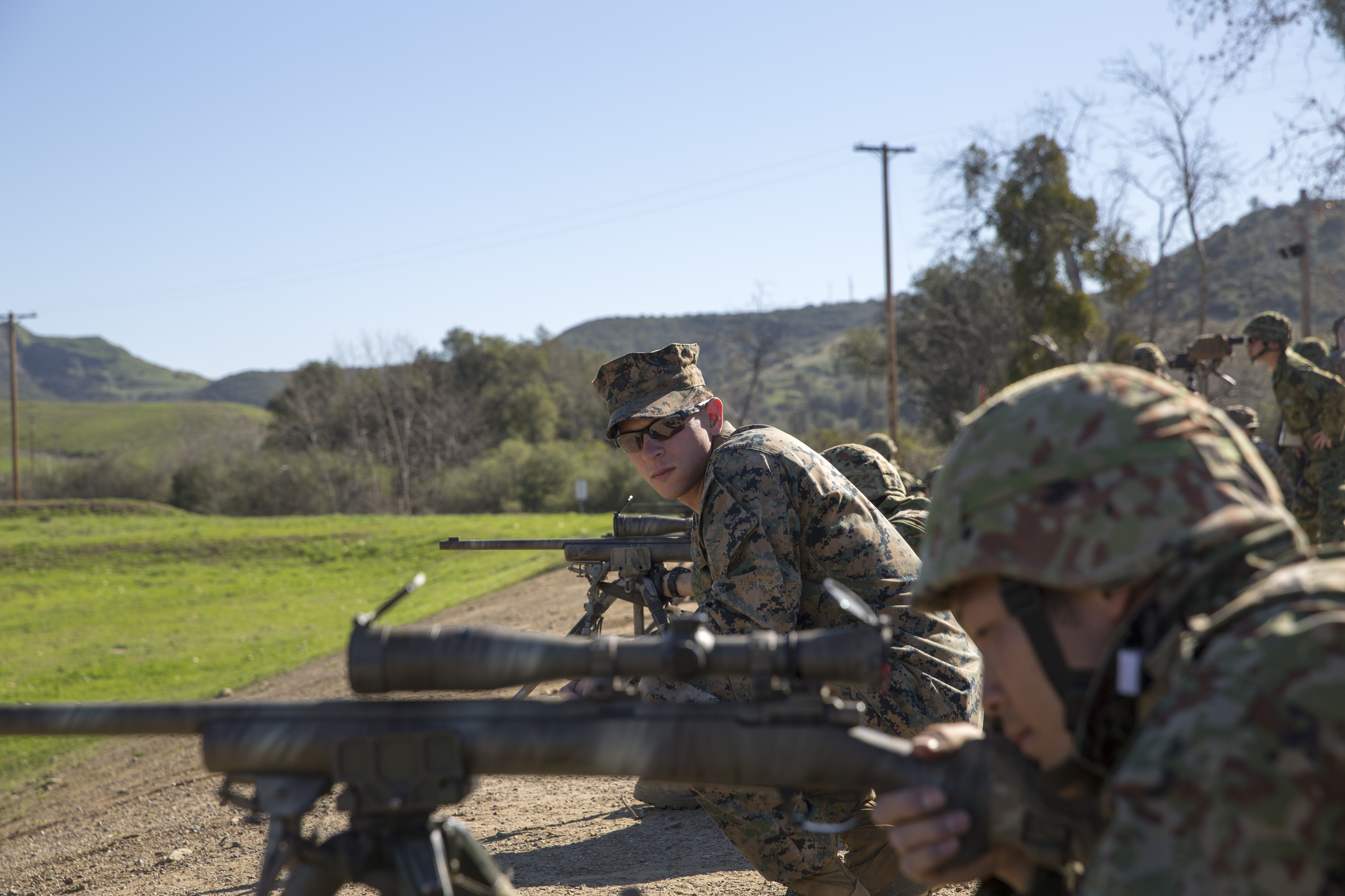 U.S. Marine Cpl. Ben Downing, mortarman with Scout Sniper Platoon, Weapons Company, 1st Battalion, 4th Marine Regiment, observes the shooting form of a Japan Ground Self-Defense Force soldier. US Marine Corps Photo
