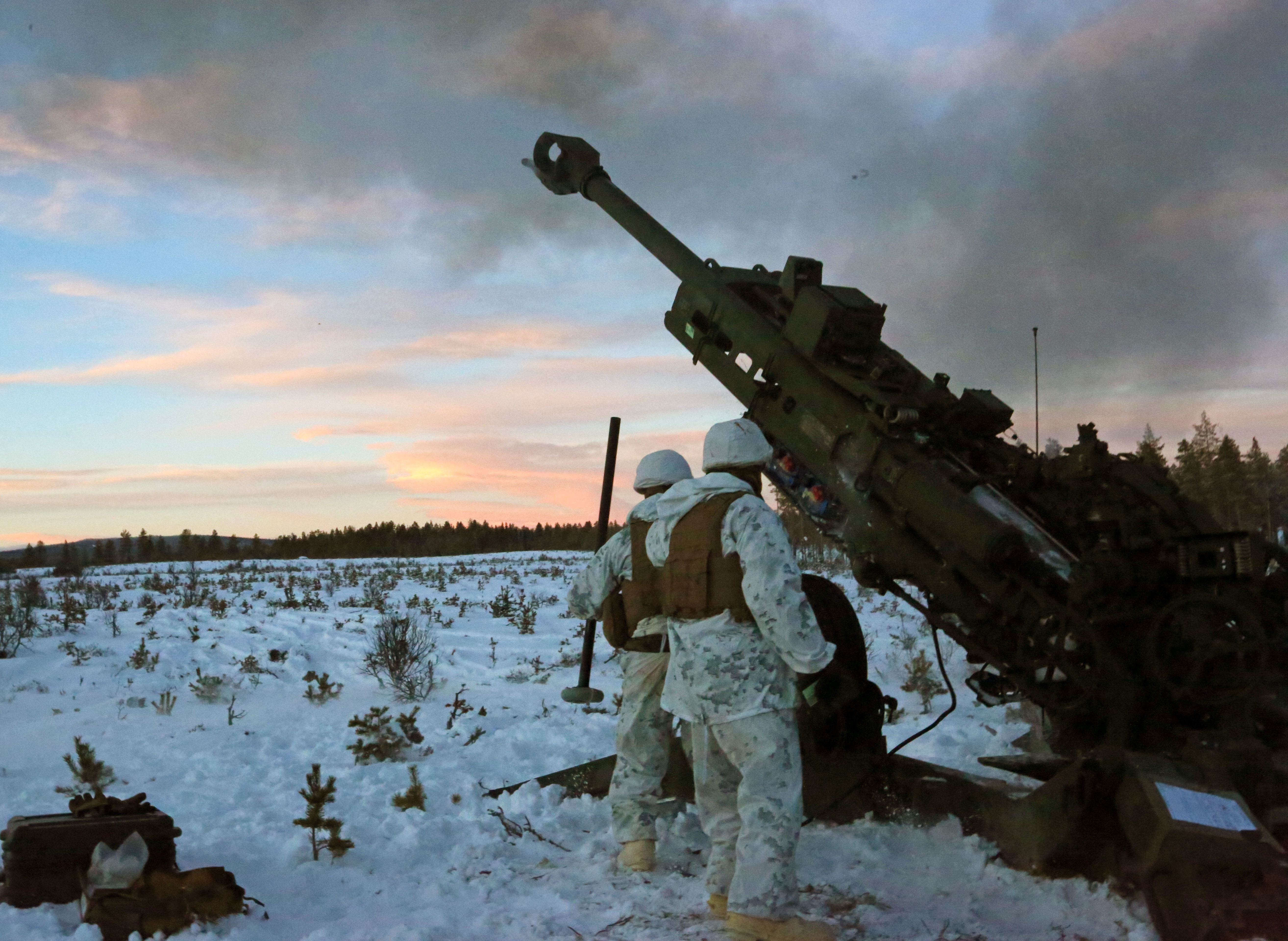 Marines with Combined Arms Company, step back as an M777 Howitzer fires a round during a live-fire shoot in Rena, Norway, Feb. 23, 2016. U.S. Marine Corps Photo