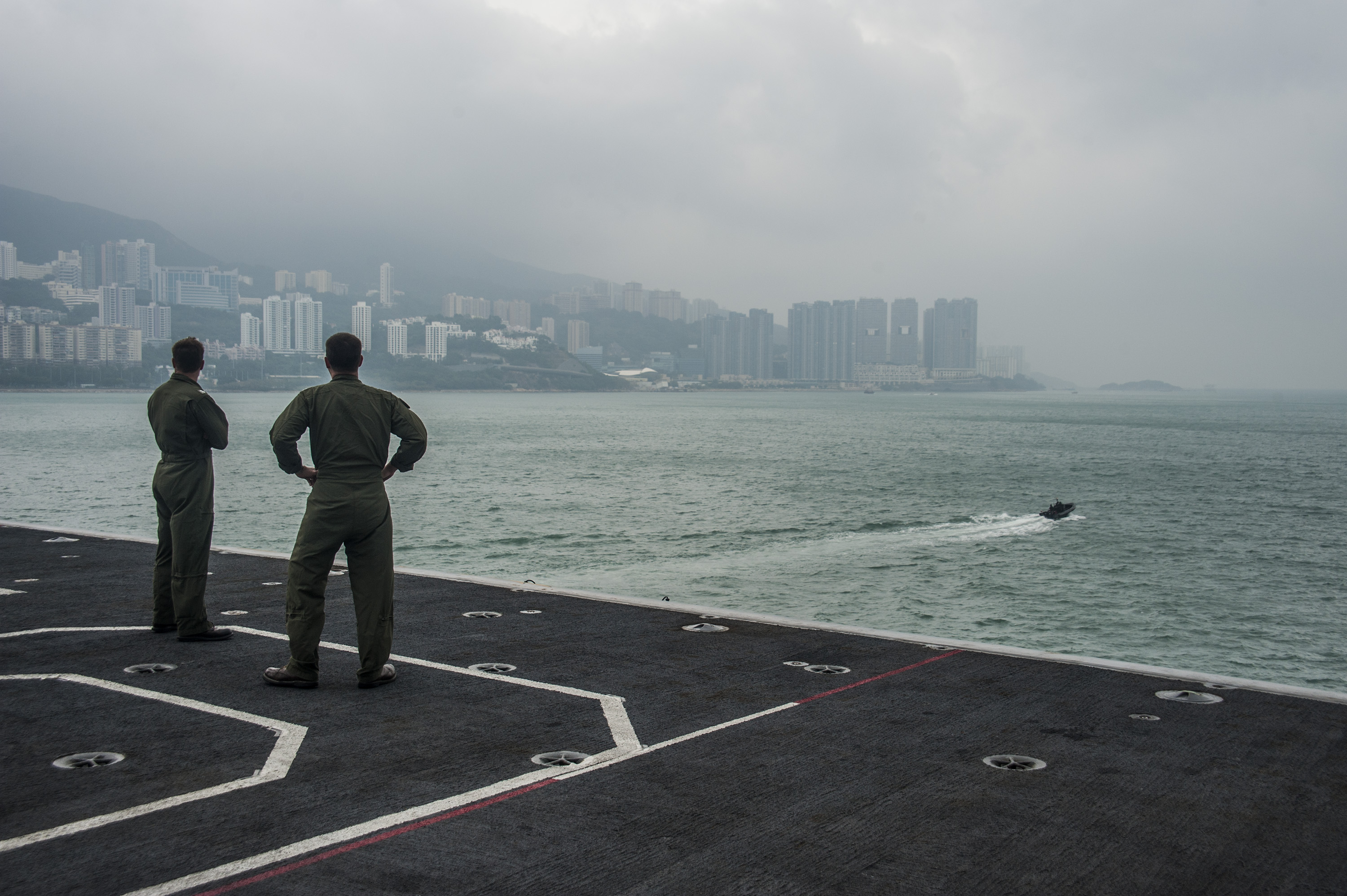 Two aviators assigned to Carrier Air Wing (CVW) 5 look out onto the Hong Kong skyline as the aircraft carrier USS George Washington (CVN-73) in 2013. US Navy Photo