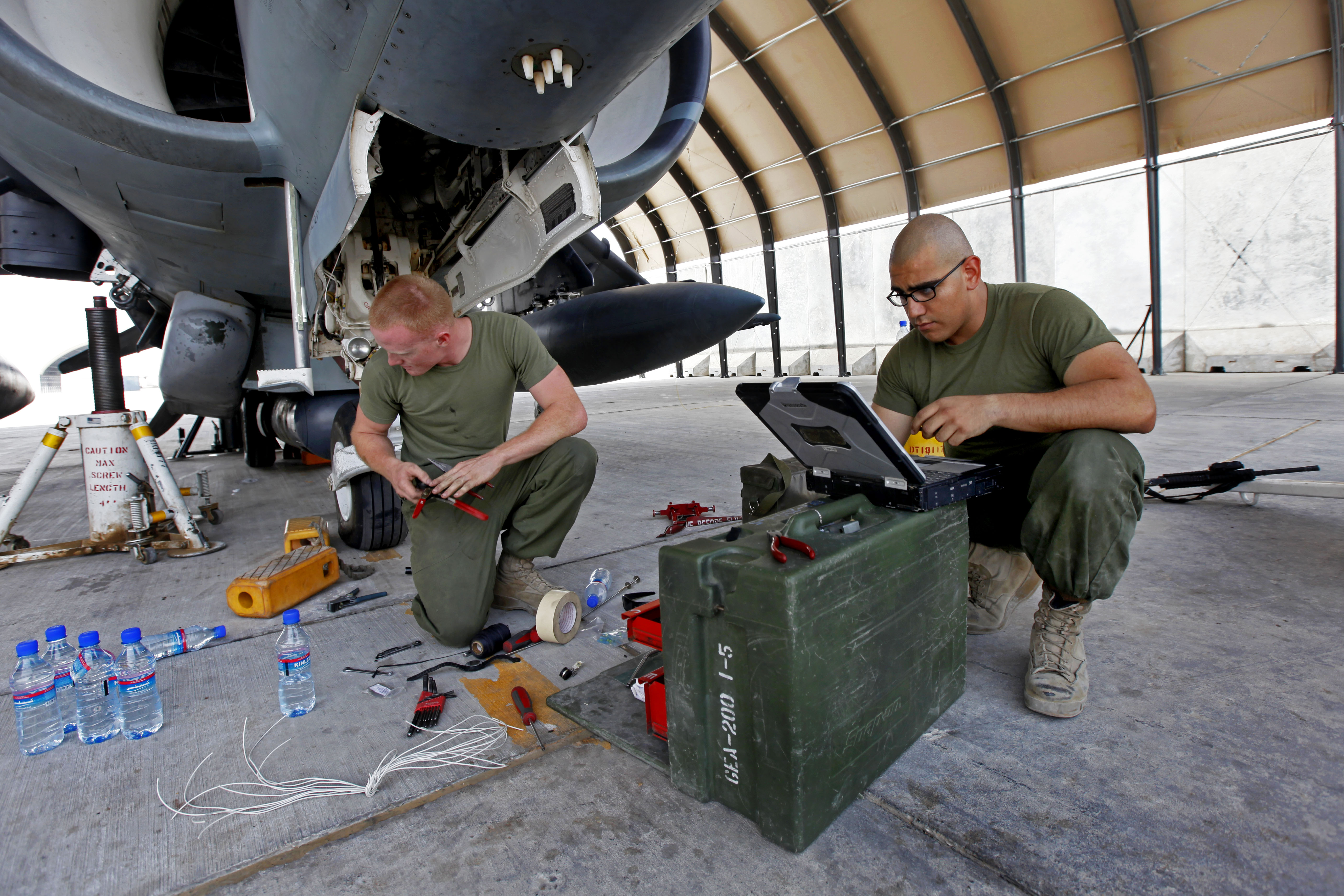 U.S. Marines Lance Cpl. Jason D. Launder, left, an avionics technician and Cpl. Noe L. Munoz, a collateral duty inspector, both with Marine Attack Squadron 311, troubleshoot and replace the landing gear system on an AV-8B Harrier. US Marine Corps Photo