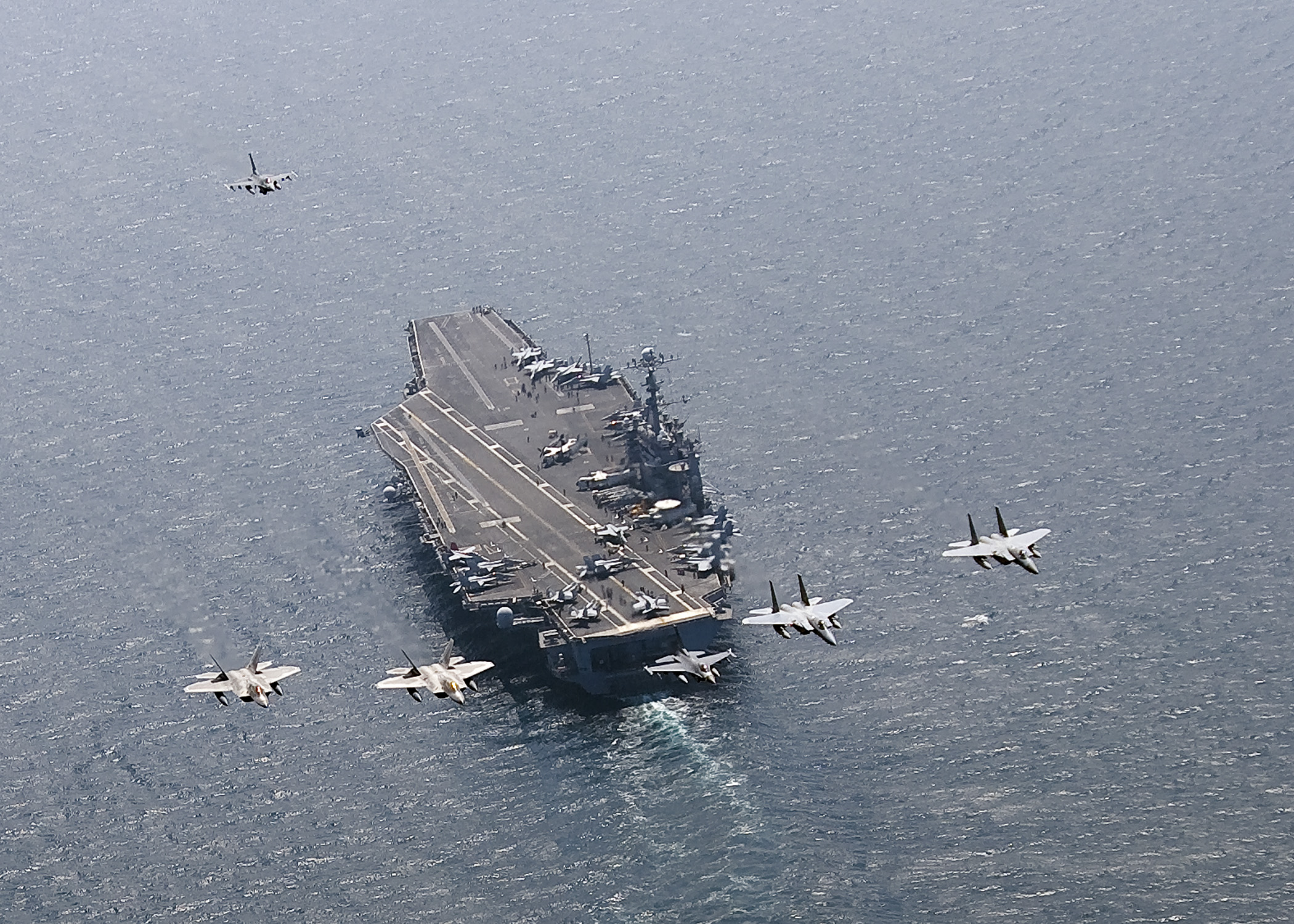 A U.S. Air Force F-16C Fighting Falcon leads a formation of F-15 Eagles and F-22 Raptors as they fly in formation over aircraft carrier USS George Washington (CVN 73) sailing through the Sea of Japan in July 2010. US Navy photo.