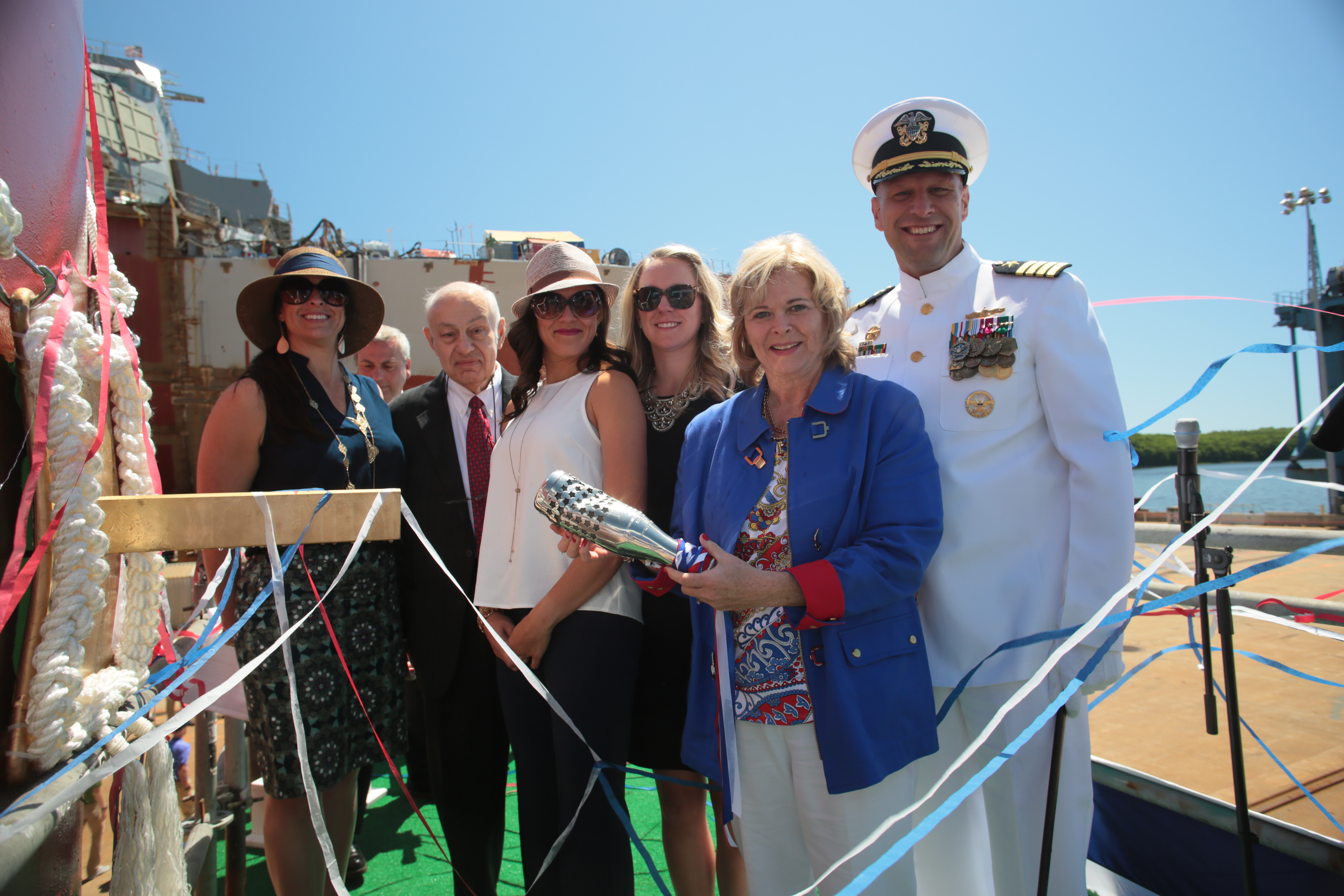 Sally Monsoor, in blue, sponsor of the future USS Michael Monsoor (DDG 1001), holds the christening bottle alongside the ship’s commanding officer, Capt. Scott Smith, her matrons of honor and Fred Harris, president of General Dynamics Bath Iron Works, which built the Zumwalt-class destroyer named in honor of Medal of Honor recipient Navy Petty Officer 2nd Class (SEAL) Michael A. Monsoor. US Navy photo.