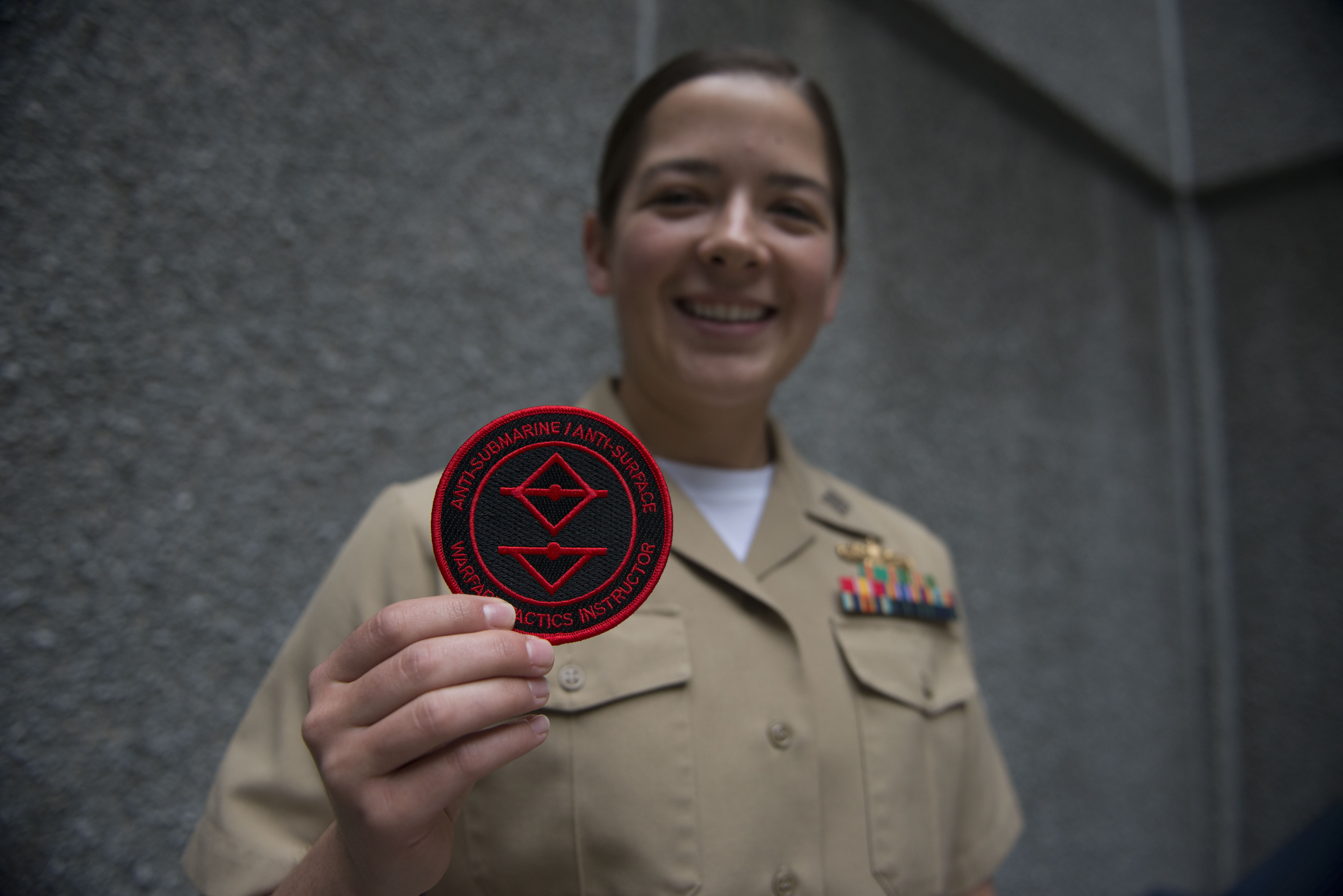 Lt. Kellie Orndorff, one of the first surface warfare officers to graduate from the Anti-Submarine/Anti-Surface Warfare Tactics Instructor course, holds up the patch they received upon graduating the Naval Surface and Mine Warfighting Development Center (SMWDC) course. US Navy photo.