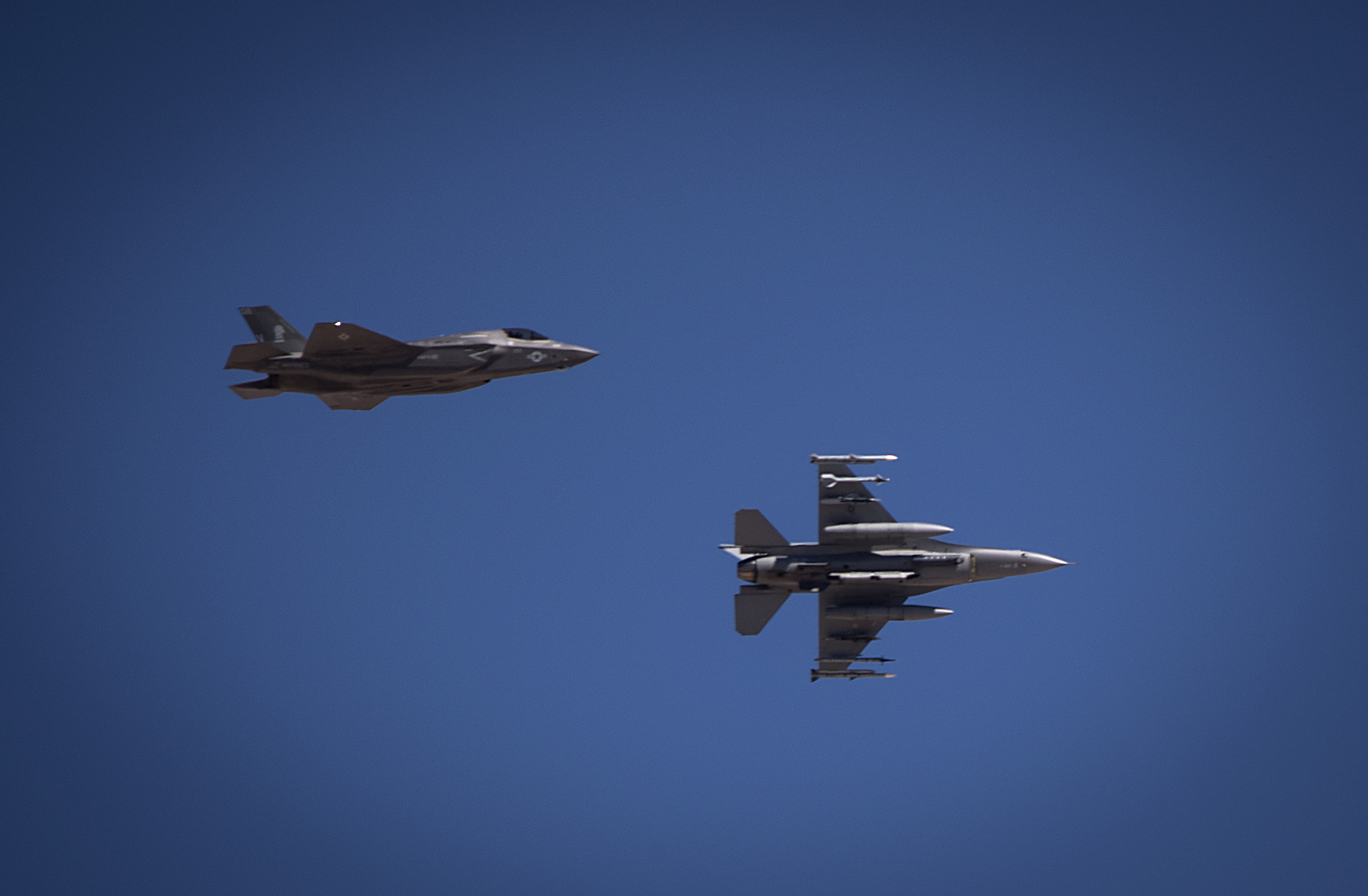 A F-35B, assigned to the Marine Fighter Attack Squadron 121 out of Marine Corps Air Station Yuma, Arizona, flies level as a F-16 Fighting Falcon from the 177th Fighter Squadron from the New Jersey Air National Guard, banks hard during approach July 15, 2016 at Nellis Air Force Base, Nevada. US Air Force Photo