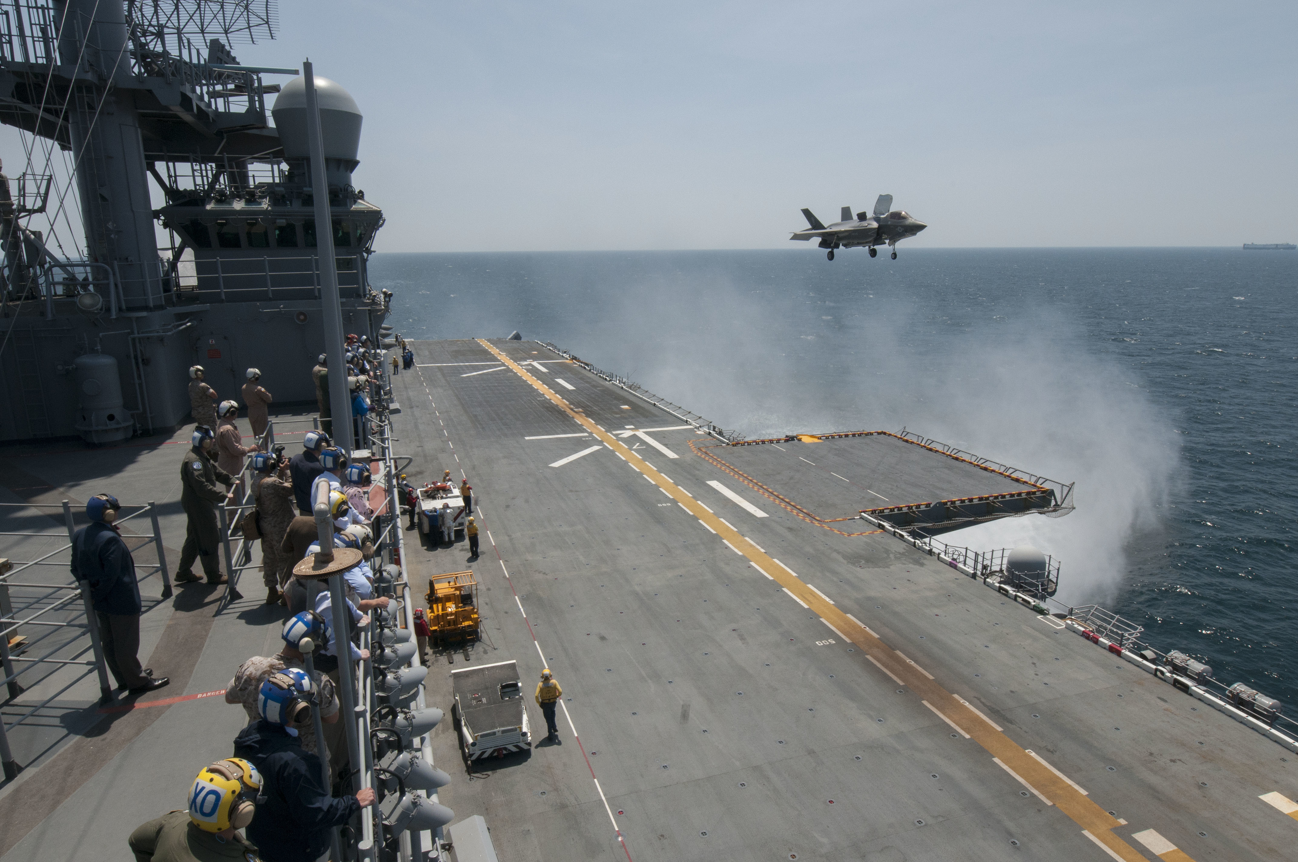 Sailors and distinguished visitors watch an F-35B Lightning II aircraft conduct vertical takeoff and landing flight operations aboard the amphibious assault ship USS Wasp (LHD 1) on May 20, 2015. US Navy photo.