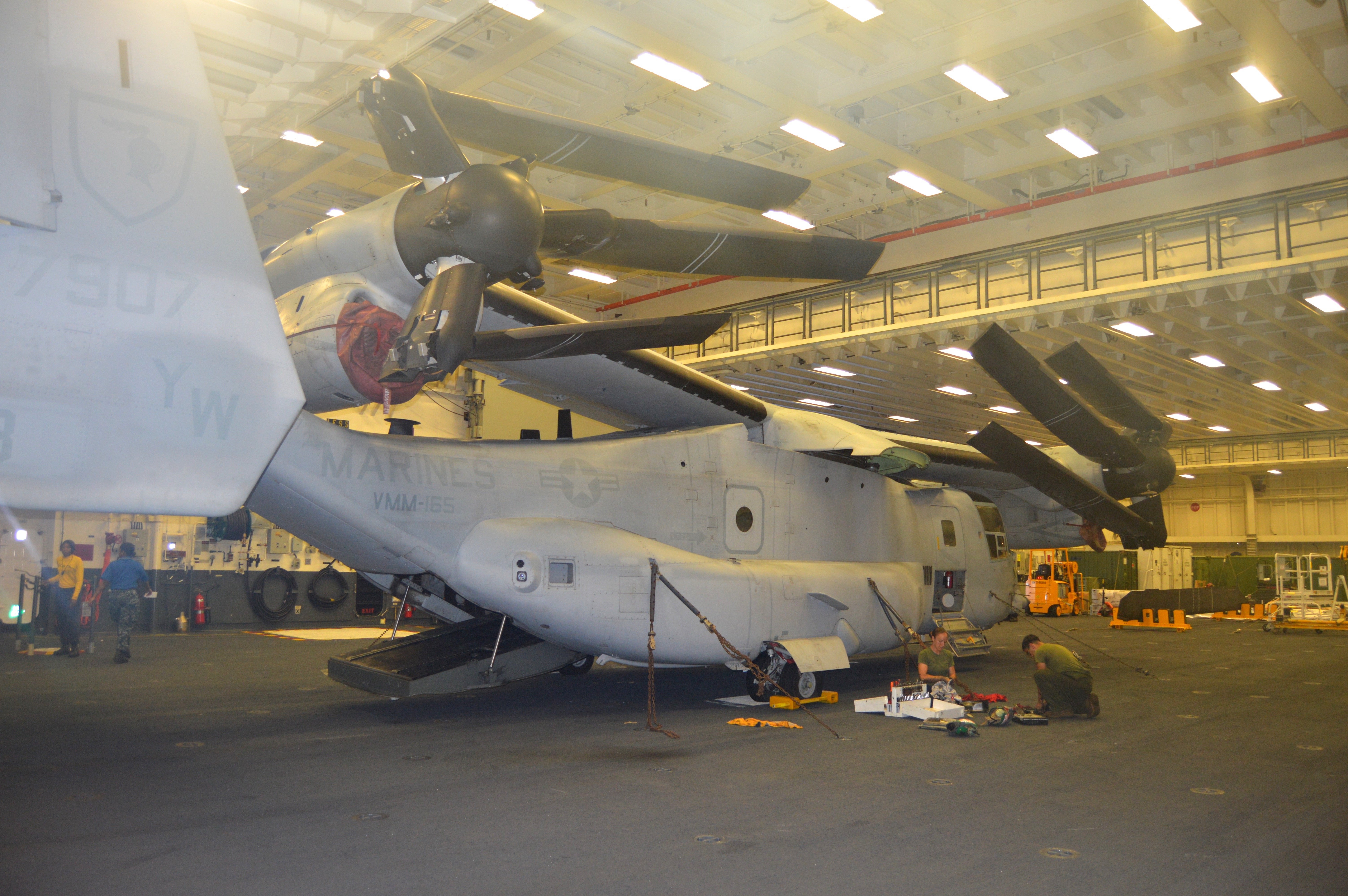 Marines from VMM-165 work on their V-22 Osprey in the hangar bay of USS America on July 16, 2016, during RIMPAC. USNI News photo.