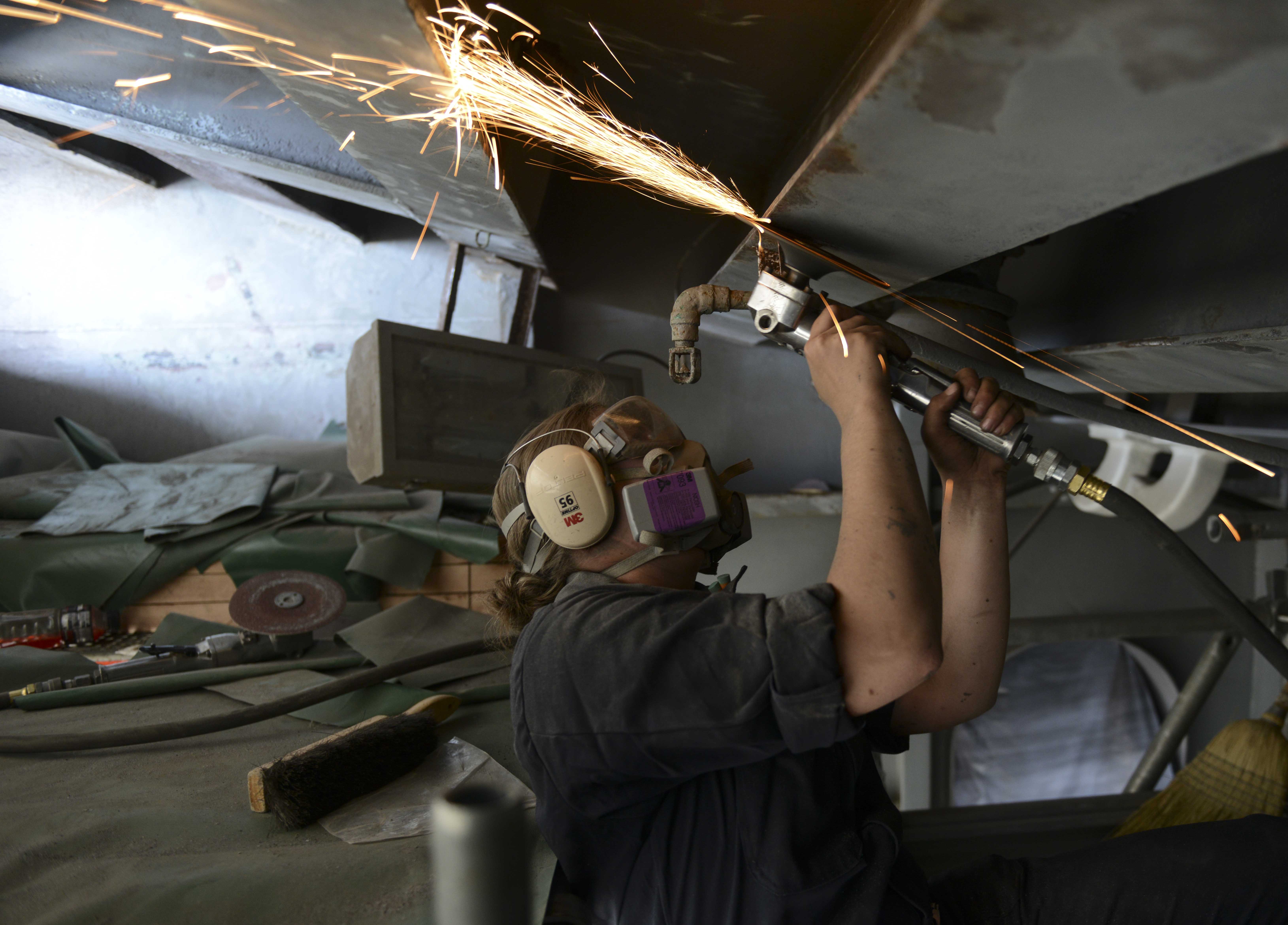 Boatswain’s Mate Seaman Kasey Ringwalda, a native of Dayton, Ore., uses a grinder to remove paint from deck station 11 on board the aircraft carrier USS Nimitz (CVN 68). Nimitz is currently undergoing an extended planned incremental maintenance availability at Puget Sound Naval Shipyard and Intermediate Maintenance Facility. US Navy Photo