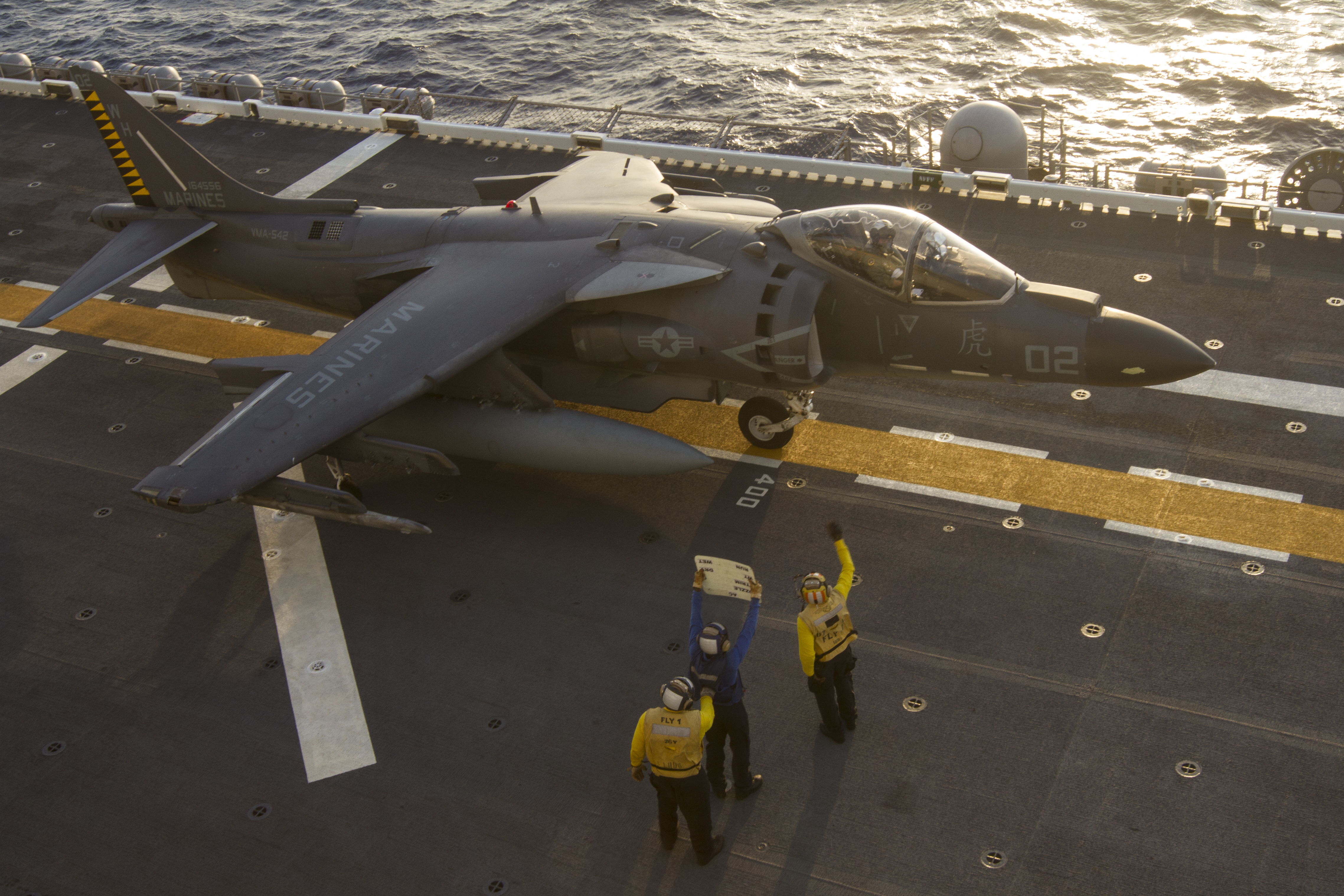 U.S. Navy flight deck aircraft controllers signal an AV-8B Harrier pilot during flight operations at sea aboard the USS Bonhomme Richard (LHD-6), while underway as part of the 31st MEU and BHR Expeditionary Strike Group, Aug. 27, 2016. US Marine Corps photo.