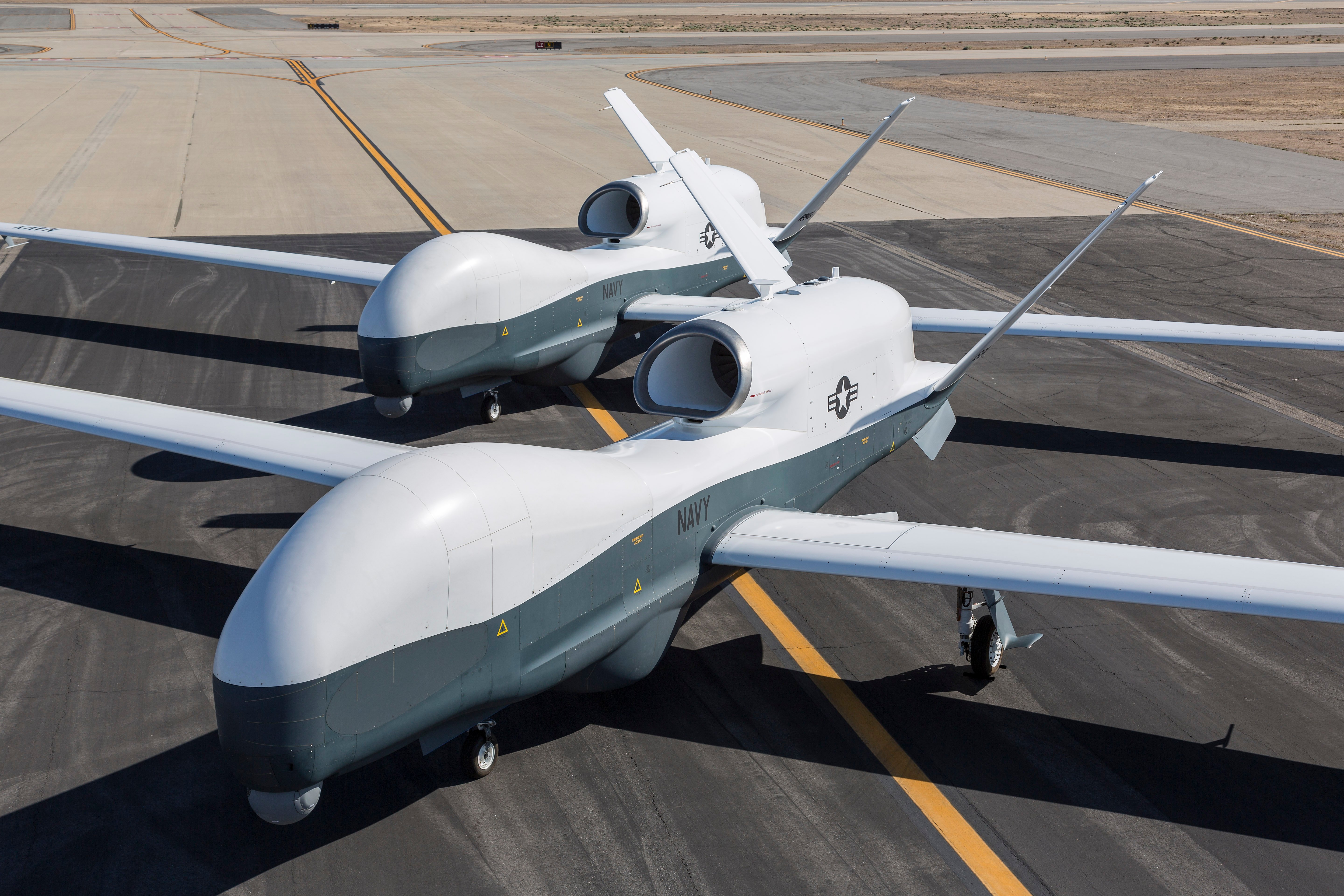 Two Northrop Grumman MQ-4C Triton unmanned aerial vehicles sit on the tarmac at a Northrop Grumman test facility in Palmdale, Calif., in May 2013. US Navy photo.