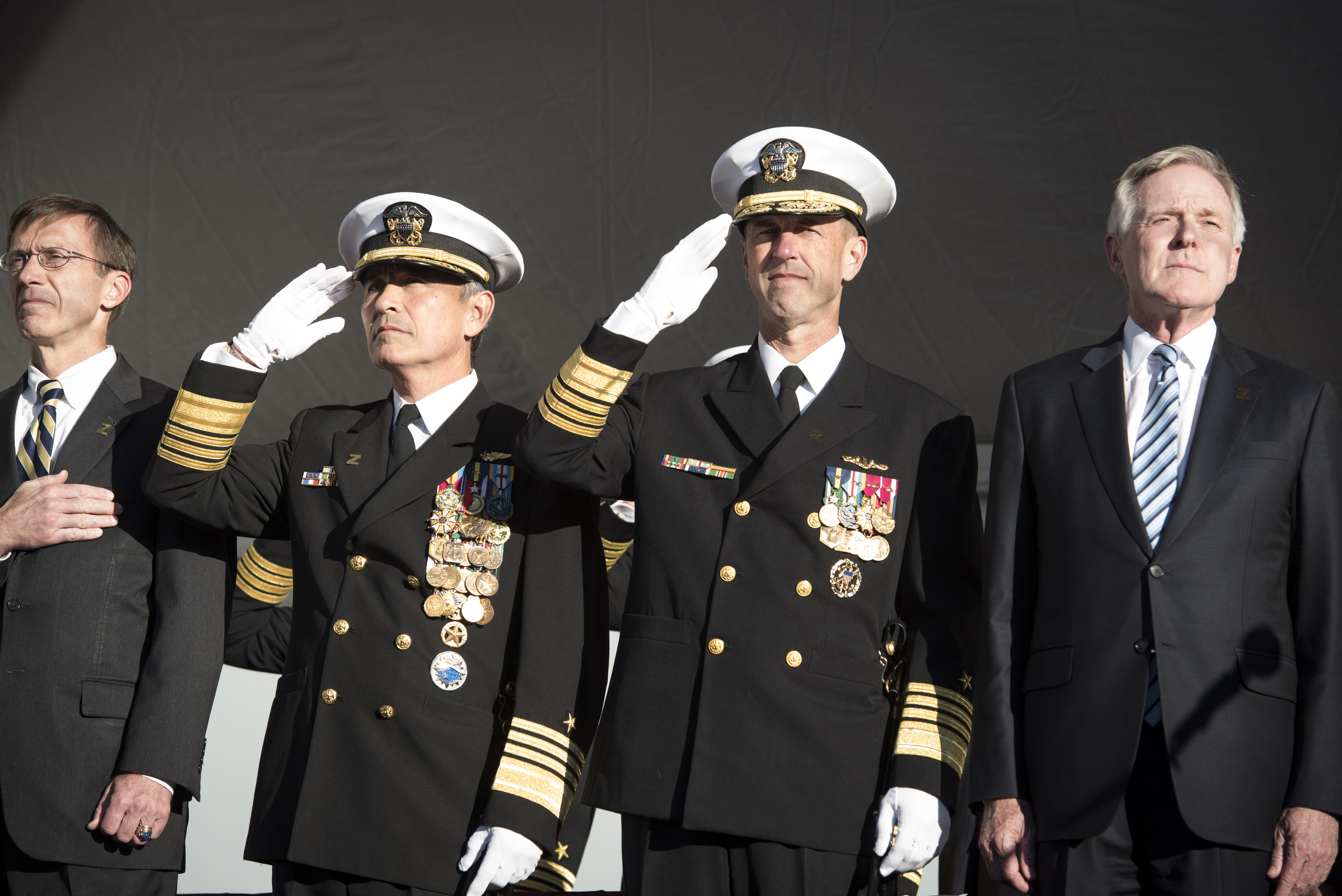 Left to right, Assistant Secretary of the Navy for Research, Development and Acquisition Sean Stackley; Commander, U.S. Pacific Command Adm. Harry Harris; Chief of Naval Operations Adm. John Richardson; and Secretary of the Navy Ray Mabus render honors for the national anthem during the commissioning ceremony for the Navy's newest and most technologically advanced warship, USS Zumwalt (DDG 1000). US Navy photo.