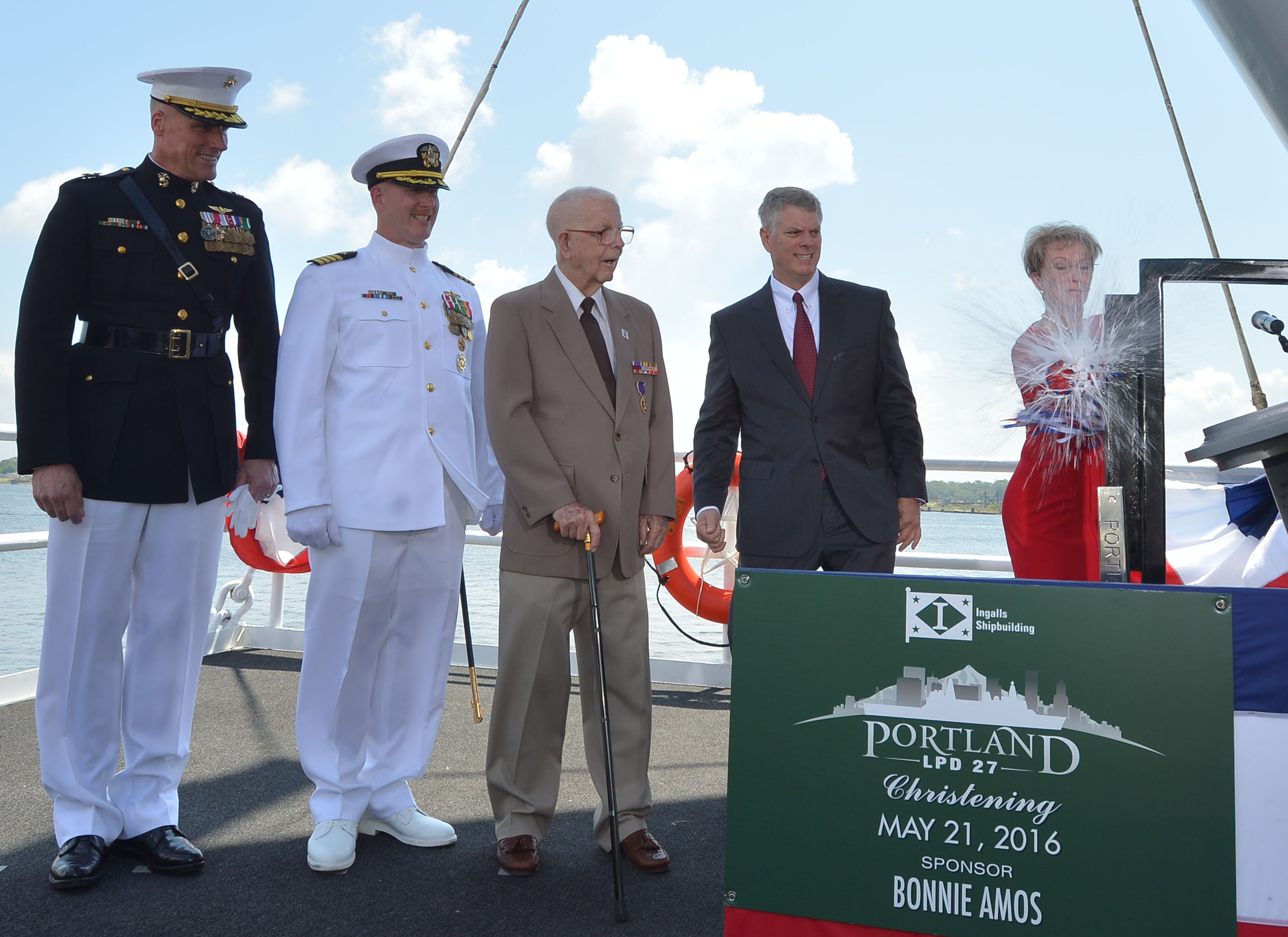 Ship Sponsor Bonnie Amos christens the amphibious transport dock Portland (LPD 27) on May 21, 2016. Amos was accompanied by (left to right) U.S. Marine Corps Maj. Gen. Christopher Owens, director of the U.S. Navy's expeditionary warfare division; Capt. Jeremy Hill, prospective commanding officer, Portland; Ted Waller, a World War II veteran who served on the first USS Portland (CA 33); and Brian Cuccias, president of Ingalls Shipbuilding. US Navy photo.